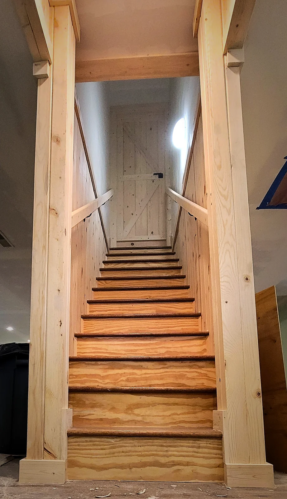 Wood-paneled basement stairwell leading down to a K-brace door